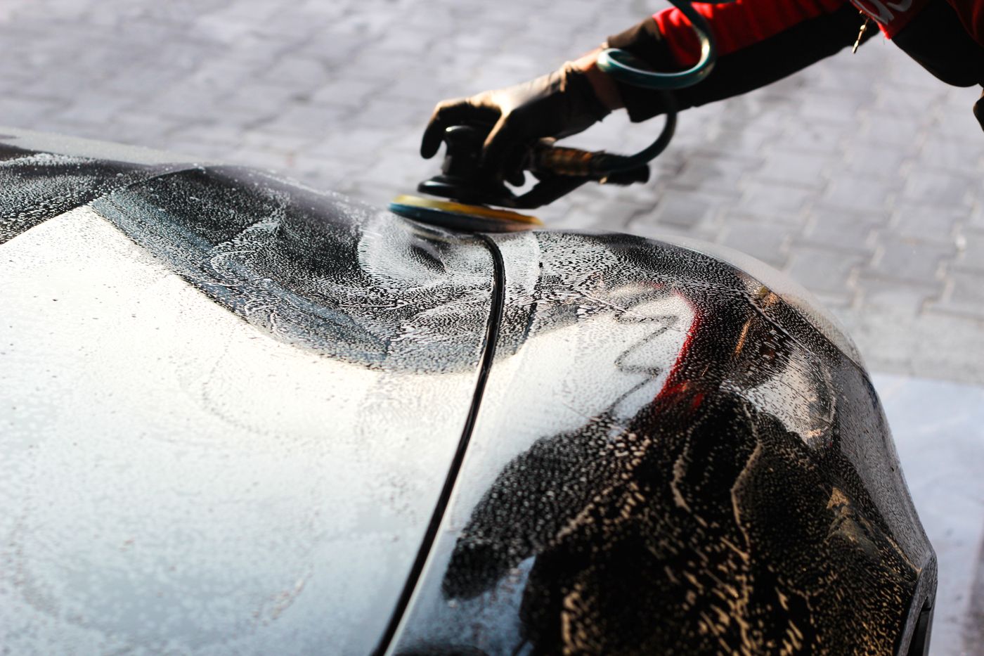 A detailer hand-polishing a car body panel, for illustration