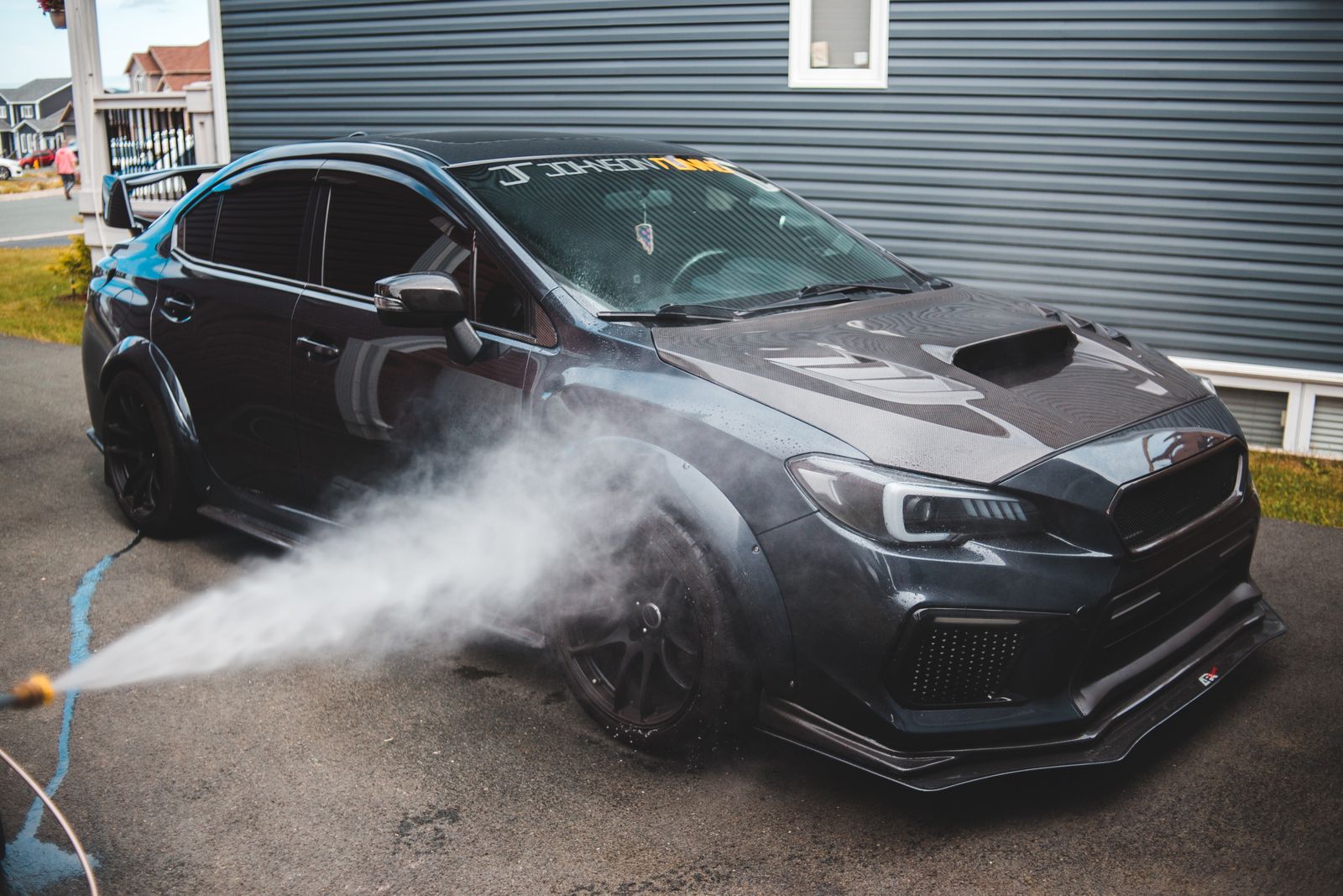 A performance car being rinsed down during a mobile detail, for illustration