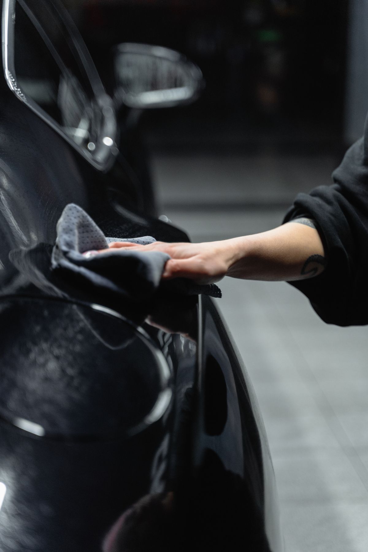 A detailer hand-buffing a car's exterior panel, for illustration